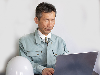 作業服を着た男性がパソコンを見る写真
