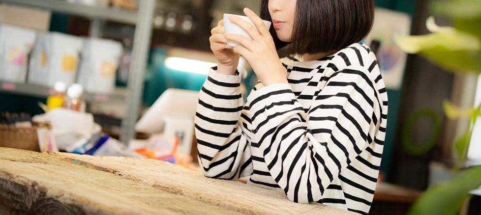 女性がカフェでゆったりとドリンクを飲んでいる写真